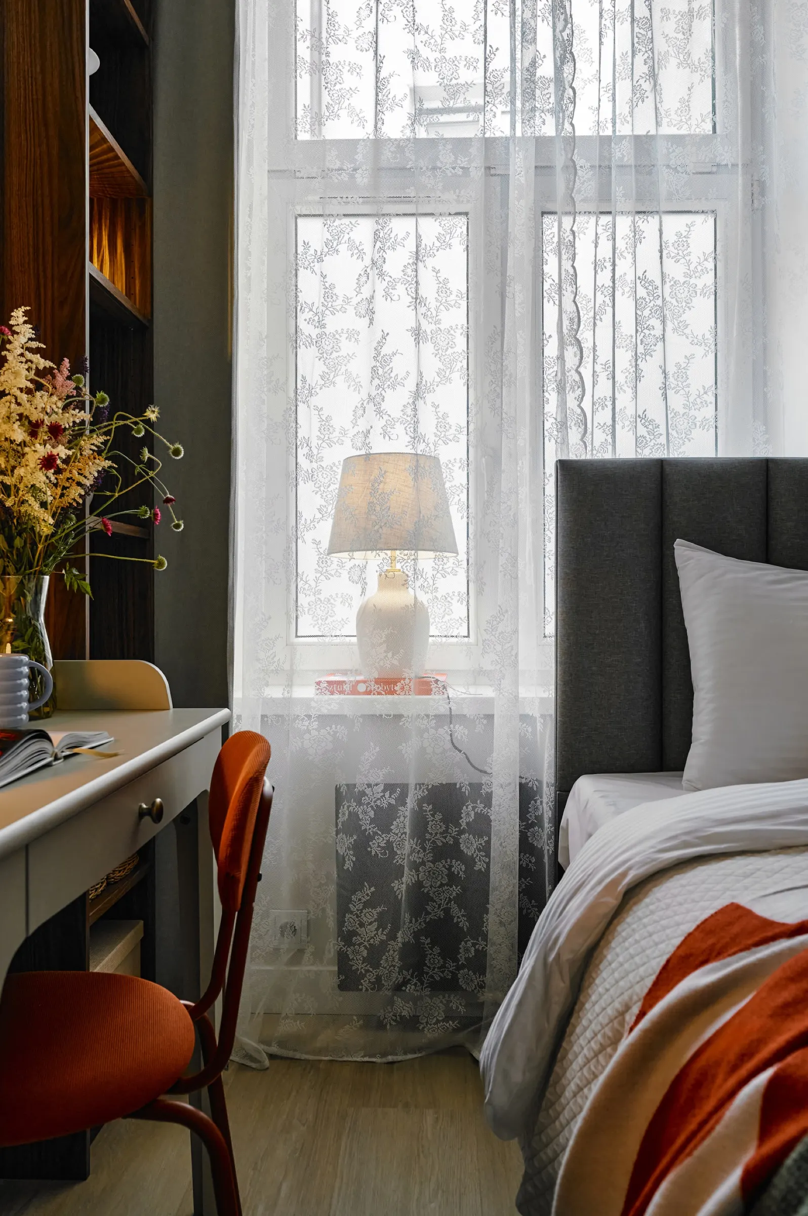 Desk chair and a lamp in the lace-curtained window