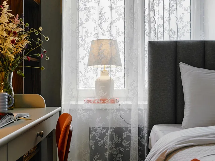 Desk chair and a lamp in the lace-curtained window