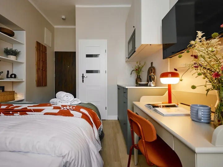Desk with a lamp and flowers beside the bed