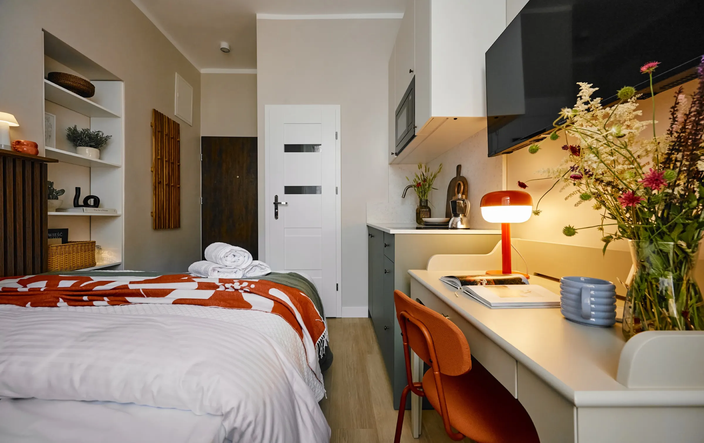 Desk with a lamp and flowers beside the bed