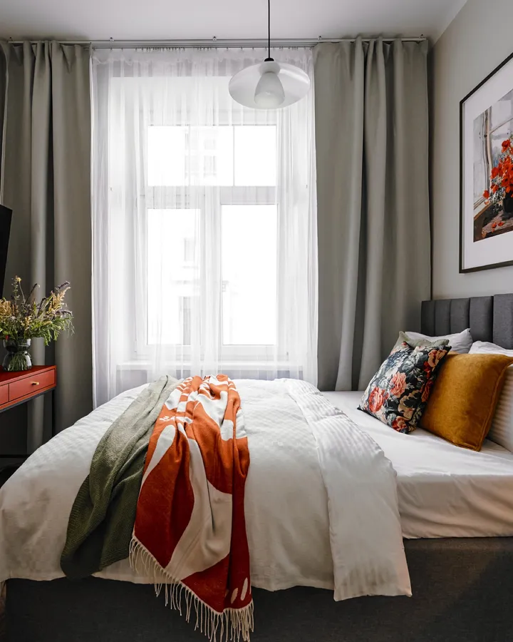 Studio with the bed, a red desk and a curtained window