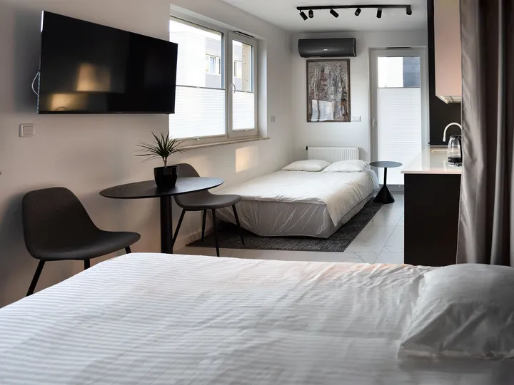 Double bed, a small table with chairs and a wall-mounted TV